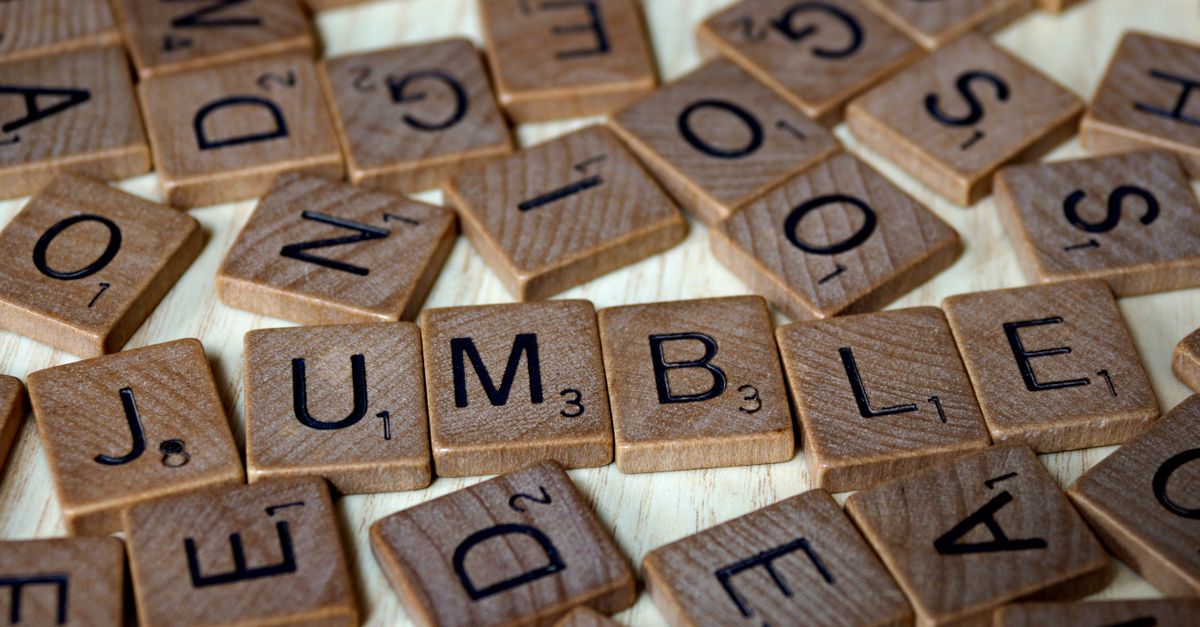 Scrabble letter tiles spelling the word JUMBLE among scattered tiles